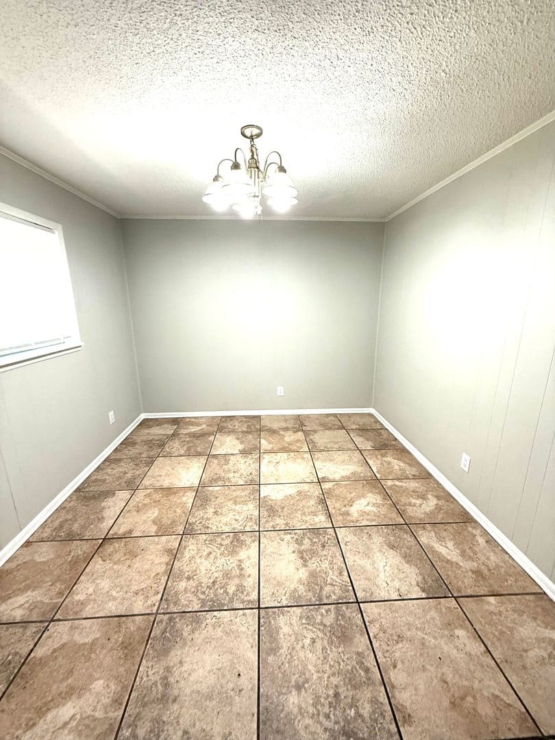 Empty tiled room with chandelier and window