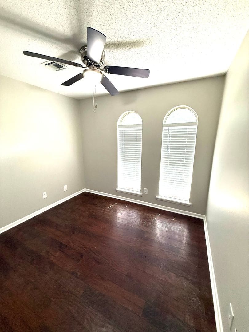 Empty bedroom with ceiling fan and arched windows