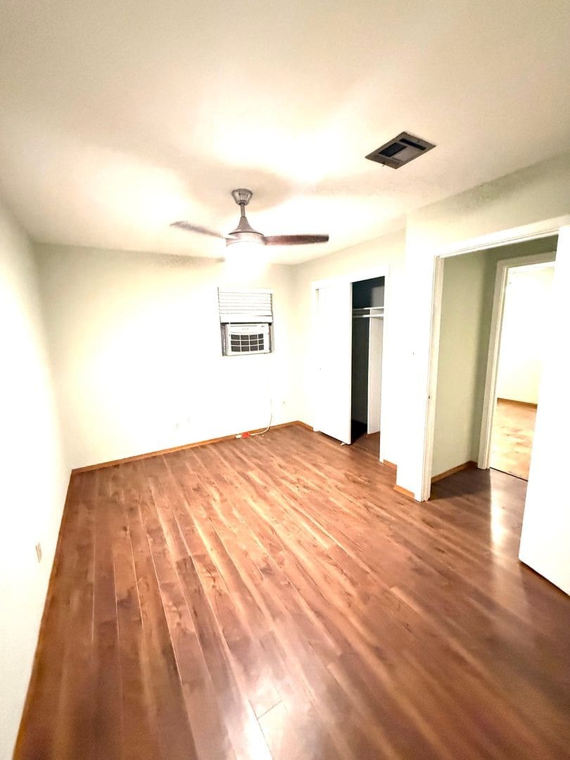Empty bedroom with hardwood floors and ceiling fan